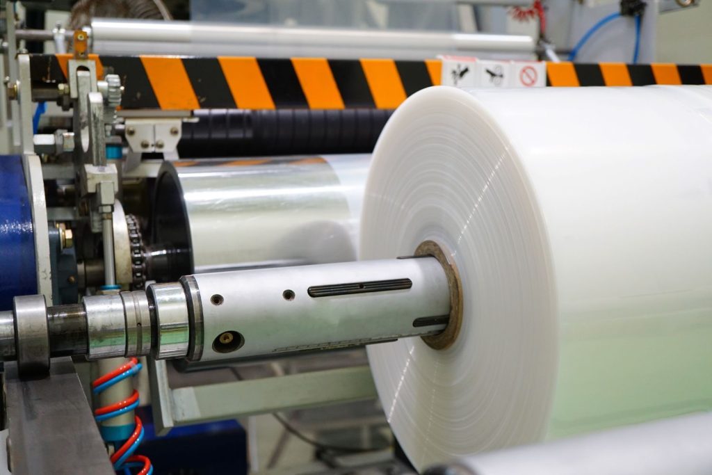 Plastic film roll on industrial machine in factory.